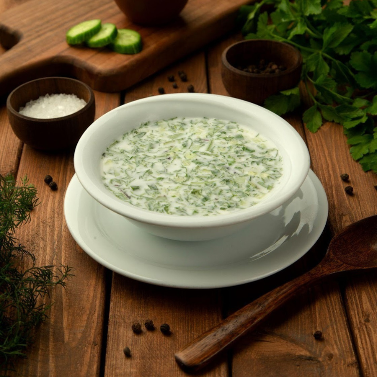 Malga branca com caldo verde em mesa de madeira